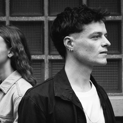 Black and white photo of a model who is wearing the Charlie earrings, part of the Icons jewellery collection, designed by Aurore Havenne. It is a pair of earrings in 925°°° silver.