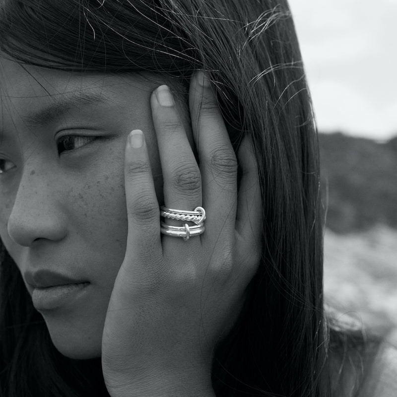 Black and white outdoor photo of a model wearing the Eden 3.2mm ring and the Ellis ring in silver.