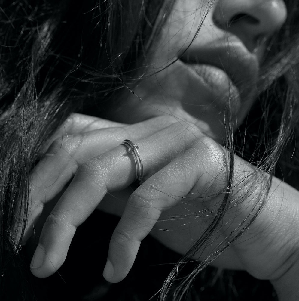 Black and white photo of a Maeva Prigent. Her hand is close to her face and she wears the Eden 2.1mm ring in silver.