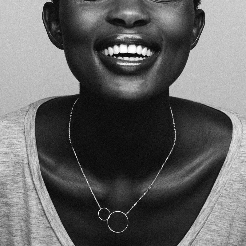 Aliane Uwimna wearing the silver Trinity necklace, a fine silver chain and three silver circles of different sizes.